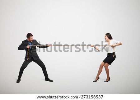 woman and man in formal wear pulling the rope over light grey background