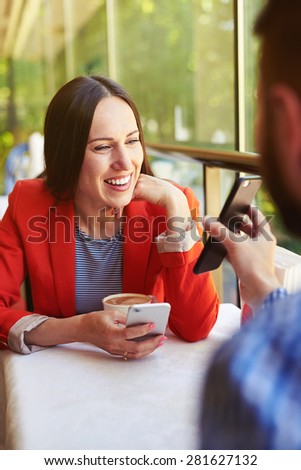man showing his cellphone to smiley young woman. loving couple at the table in a cafe
