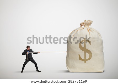 small businessman pulling the rope a big bag of money over dark background