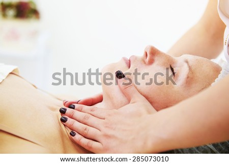 doctor doing facial massage for beautiful young woman at beauty studio