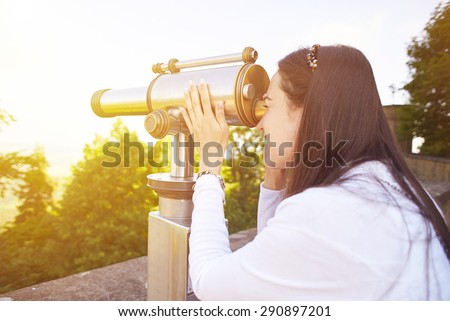 young woman tourist watching at the beautiful landscape from the telescope