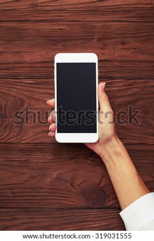view from above on womans hand with smartphone over wooden background
