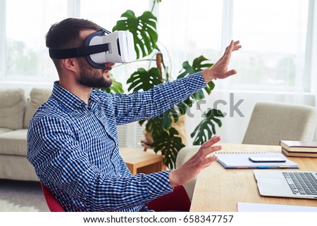 Mid shot of bearded sir in virtual reality glasses working while sitting at table Photo stock © 