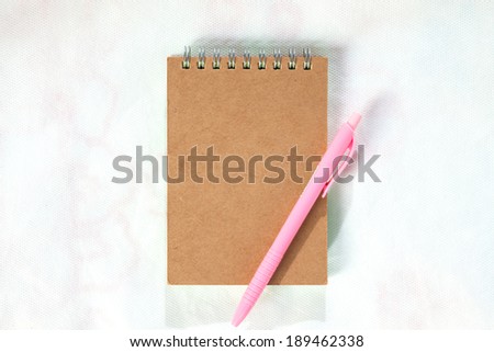 Brown front cover notebook with pink pen isolated on Mattress White background