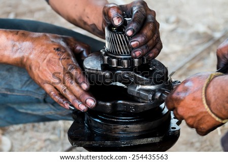 mechanic hands fixing engine power transmission gears box