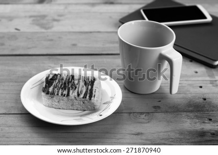 black and white notebook with coffee cup and cake on wood table