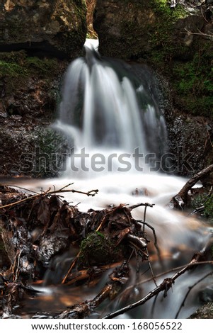 Forrest Waterfall. Red leaves on the ground, barren trees, little creek running through the woods in Bavaria, Germany