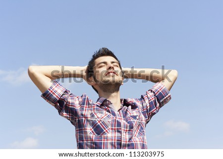 Young happy man relaxing at the sun and dreaming with closed eyes