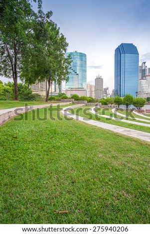 Grass field in Bangkok city Benchakitti Park with modern office building background
