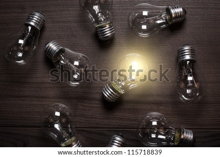 glowing bulb over wooden background uniqueness concept
