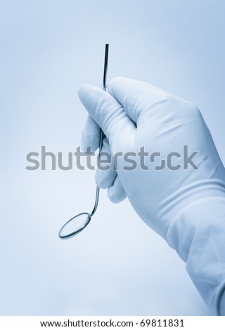 hand of dentist holding mirror during patient examination
