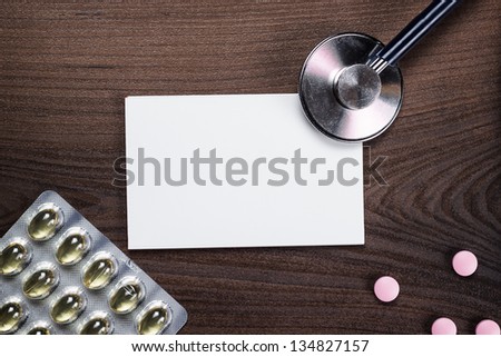 blank notebook statoscope and pills on brown wooden table