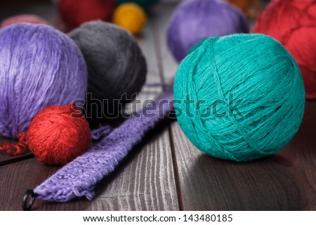 knitting needles and balls of threads on wooden table
