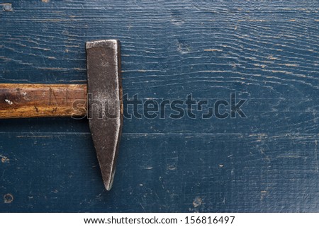old rusty hammer on blue wooden background