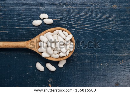 old wooden spoon full of kidney beans on the blue table
