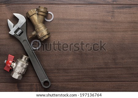 adjustable wrench and pipes on the wooden background