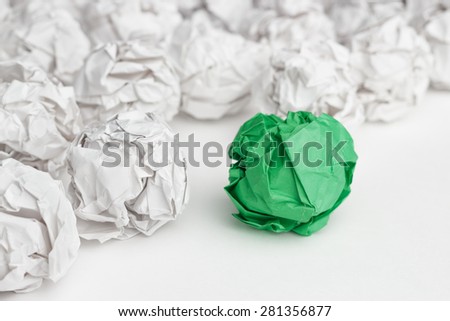 overhead shot of crumpled paper in oder and green one standing out. great idea concept on the white office table