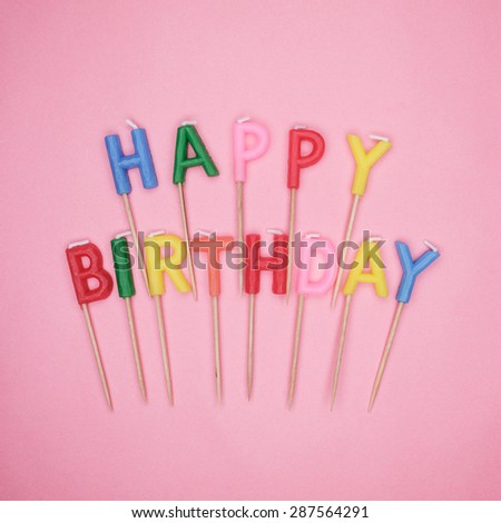 colorful letter-shaped happy birthday candles on pink background