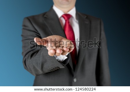 Well dressed business man is outstretching his hand. Background is blue/black.
