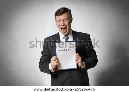 Crying business man holds a file with german text Kundigung (in engslish dismissal)