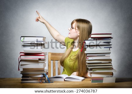 Young female teacher at a table with books pointing the finger back