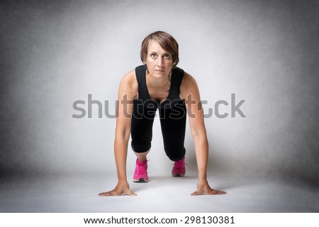 Image of running middle aged handsome woman in running start position