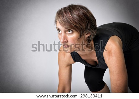 Image of running middle aged handsome woman in running start position