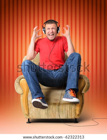 Man in headphones has jumped up in an armchair - concept