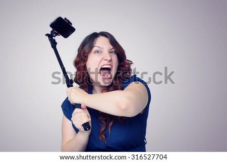 Young screaming woman with a stick for self. Girl in a fury