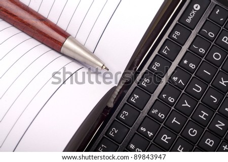 Open notebook with keyboard and pen isolated on white