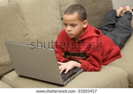 Young boy relaxing on the couch surfing the internet on a laptop