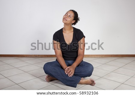 African American woman sitting on floor, looking up