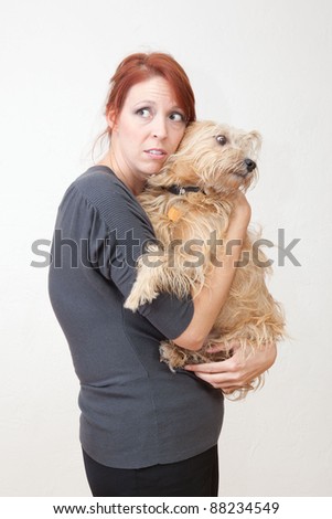 Sad red haired woman holding small terrier.