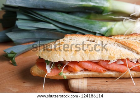 Smoked Salmon sandwich on baguette garnished with large green onions.