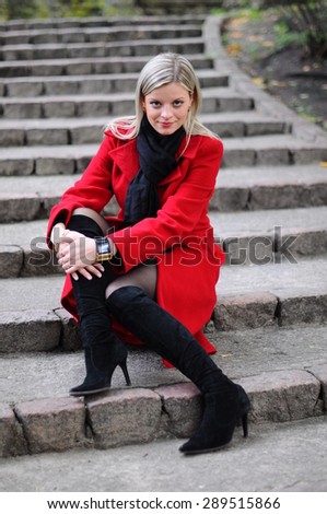young beautiful woman in a red coat at the autumn park