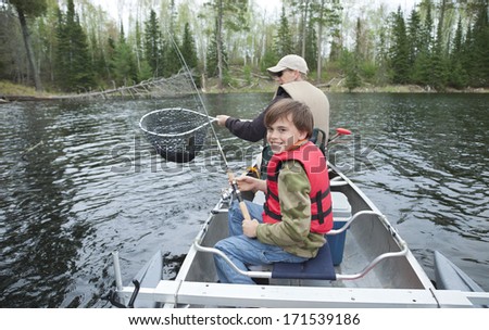 A young fisherman in a canoe smiles after seeing his walleye netted