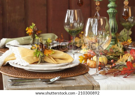 Fall dining place settings on rustic table and dark red wall
