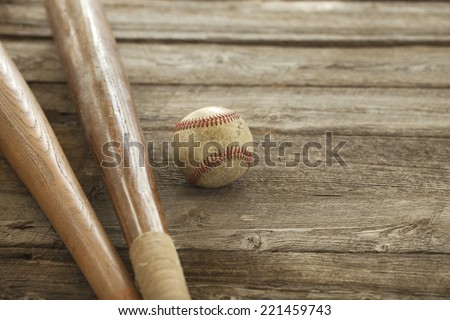 An old baseball and wooden bats on a rough wood surface