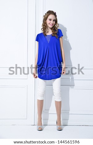 full-length portrait of fashion model in blue dress standing posing in studio