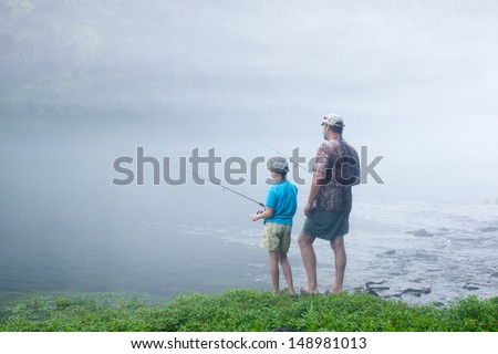 Father and son in the early misty morning fishing