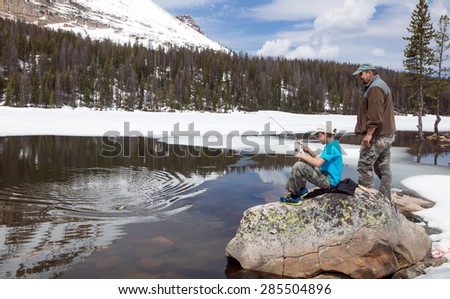 The child pulls a fish from alpine lakes.  Father ready to help.  Mirror Lake,  Uinta-Wasatch-Cache National Forest, Utah