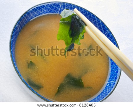 Japanese miso soup with wakame flakes.  Focus on chopstick end.