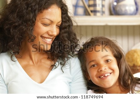 Pretty mother grins as her cute little girl smiles showing her missing teeth