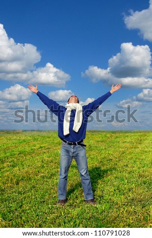 happy young man raising his hands in the summer field