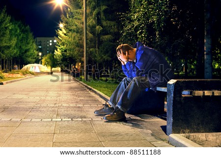troubled teenager with hidden face sitting in the night park