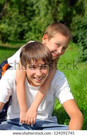 Happy little brother embrace his older brother in the summer park