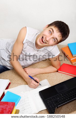 Cheerful Teenager doing Homework on the Sofa at the Home