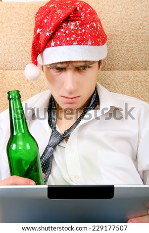 Troubled Teenager in Santa Hat with Tablet Computer and Bottle of the Beer