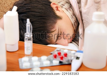 Sick Teenager sleeping on the Sofa with Pills on foreground