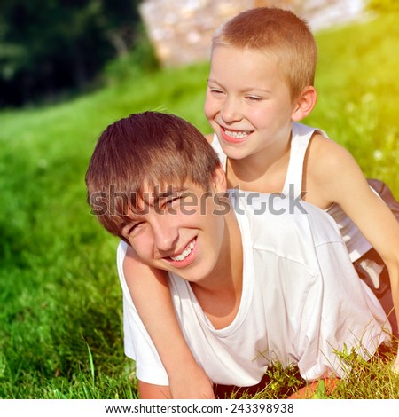 Happy Brothers on the Grass in the Summer Park